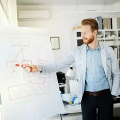 Mężczyzna z rudym zarostem wyjaśnia na tablicy schemat, który ilustruje strategię dyferencjacji.
