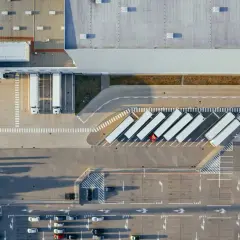 Widok z lotu ptaka na magazyn z systemami WMS, gdzie ciężarówki czekają na rozładunek.