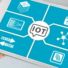 Tablet pokazuje schemat przemysłowego internetu rzeczy (IoT) z ikonami symbolizującymi dane, połączenia i urządzenia.
