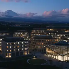 Nowoczesne budynki z oświetlonymi oknami i górą Fudżi w tle o zmierzchu.
