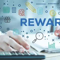 System sugestii pracowniczych. Ręce na kalkulatorze, słowo REWARDS i ikony symbolizujące pracę i nagrody.