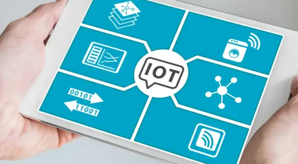 Tablet pokazuje schemat przemysłowego internetu rzeczy (IoT) z ikonami symbolizującymi dane, połączenia i urządzenia.