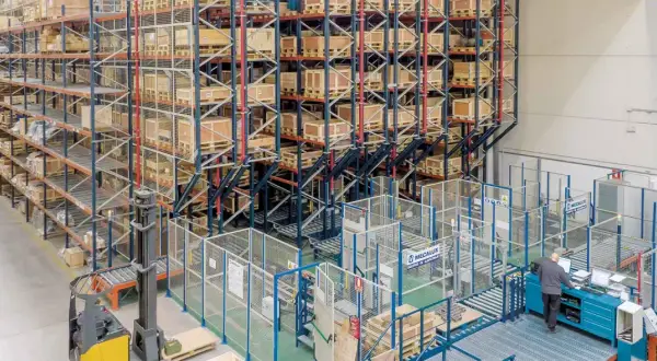 Wysoki regał magazynowy z paletami i wózek widłowy w nowoczesnym centrum logistycznym.