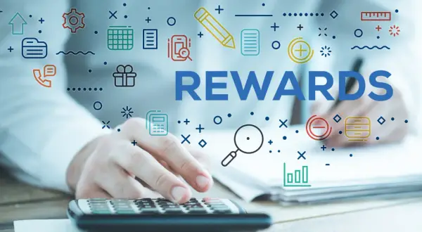System sugestii pracowniczych. Ręce na kalkulatorze, słowo REWARDS i ikony symbolizujące pracę i nagrody.