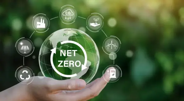 Dłoń trzymająca Ziemię z napisem "NET ZERO", otoczoną ikonami symbolizującymi zrównoważony rozwój i neutralność klimatyczną.
