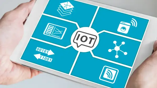 Tablet pokazuje schemat przemysłowego internetu rzeczy (IoT) z ikonami symbolizującymi dane, połączenia i urządzenia.