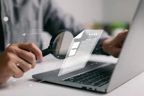 Analiza dokumentu za pomocą lupy i laptopa. To pokazuje, jak działa ocr co to jest i jak ułatwia pracę z danymi.