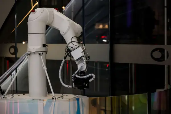 Białe ramię robota z kamerą, symbol postępu w dziedzinie generatywnej sztucznej inteligencji, gotowe do uchwycenia przyszłości.